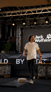 Marlon Blatz von Ganesha’s room bei einem Firmen- und Eventyoga-Auftritt auf einer Jack Wolfskin Bühne mit Yogamatte und Meditationskissen.